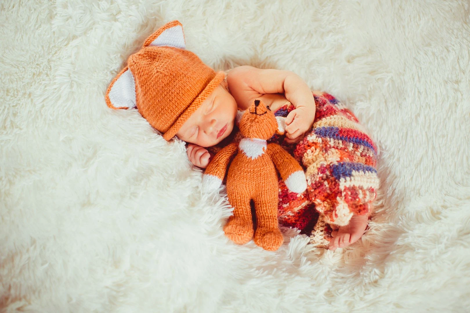 baby-holds-little-fox-toy-sleeping-white-pillow.jpg