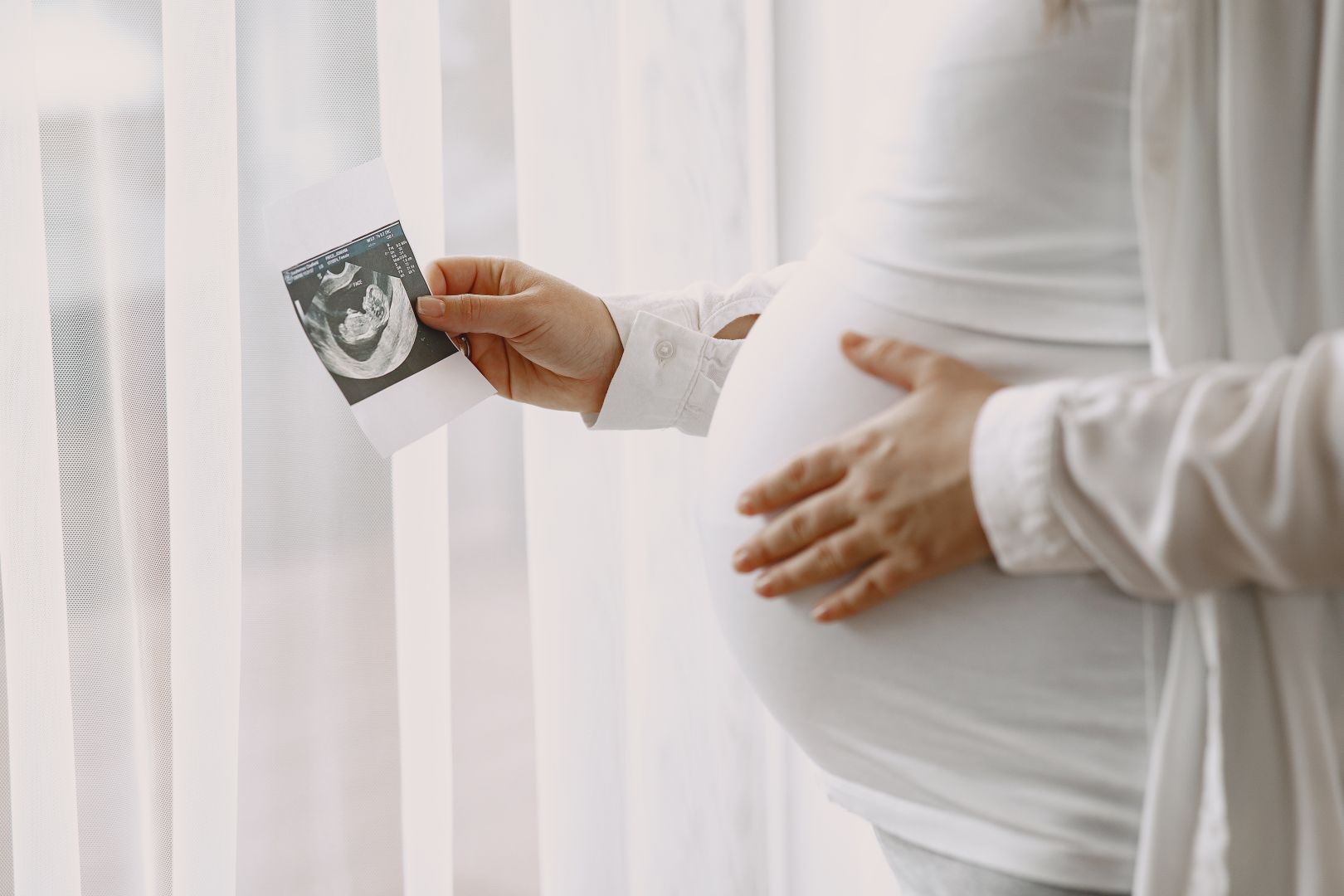 pregnant-woman-standing-by-window-looking-photo.jpg